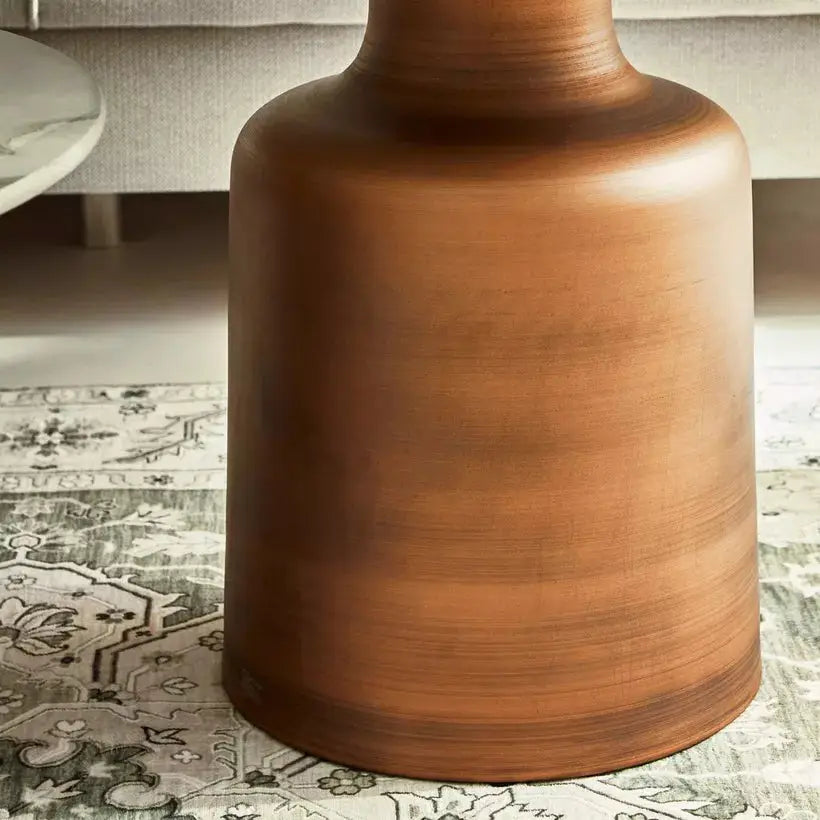 a brown vase sitting on top of a rug